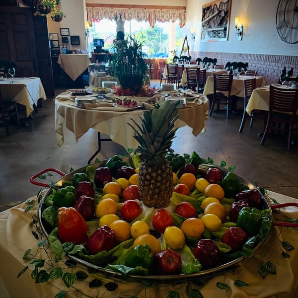A large paella pan filled with colorful fruits and vegetables, with a pineapple in the center.