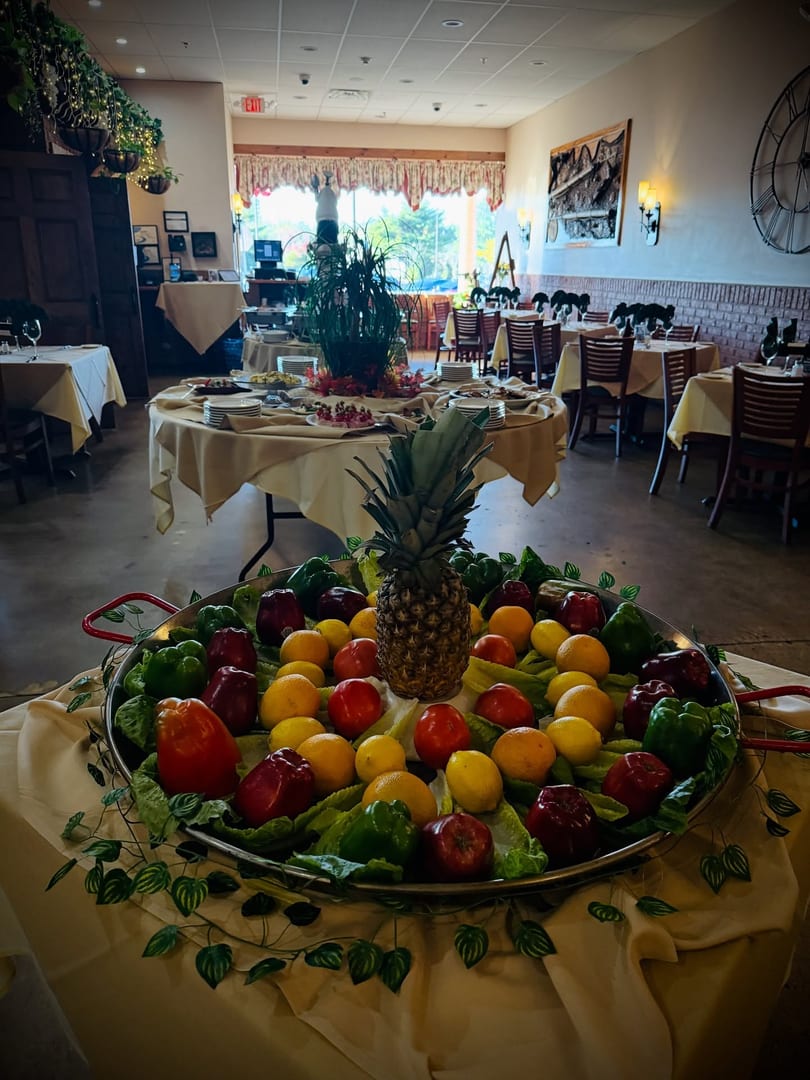 A large paella pan filled with colorful fruits and vegetables, with a pineapple in the center.